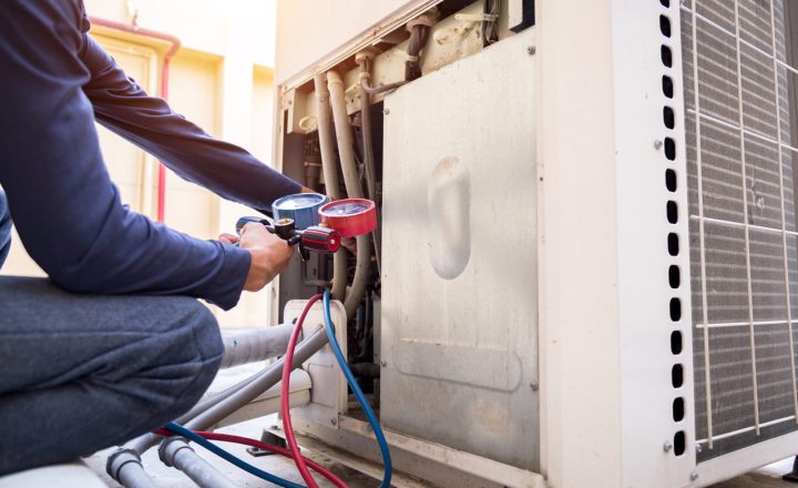 A skilled technician with specialized measuring equipment for filling the air conditioner unit for inspection purposes and carefully manipulates the gauges and hoses, ensuring proper connections.