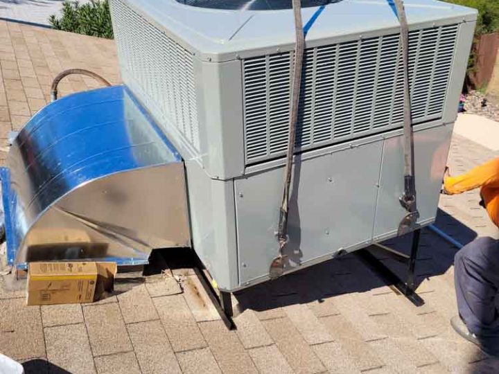 Professional experts carefully working on installing a packaged AC on a residential rooftop
