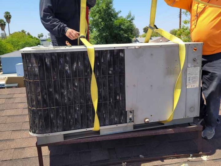 Technicians replacing an old AC unit from a residential rooftop